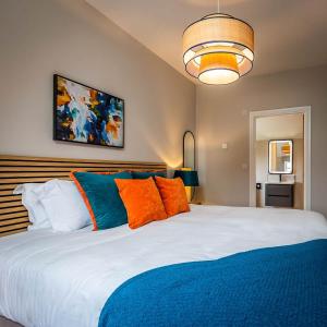 sypialnia z dużym łóżkiem z pomarańczowymi i niebieskimi poduszkami w obiekcie The Birches, Ashlin Farm Barns w mieście Lincoln