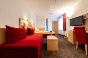 a hotel room with a red couch and a bed at Gasthaus Hotel Zum Mohren in Niederstotzingen