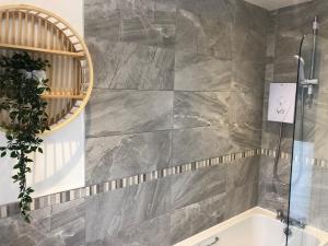 a bathroom with a bath tub and a mirror at Barber House, Hoyland with two allocated parking spaces in Hoyland Nether +15 photos