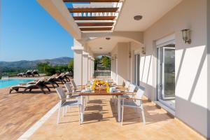 un patio con mesa, sillas y piscina en Villa Kamos, en Archangelos