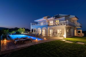 a large white house with a swimming pool at night at Villa Kamos in Archangelos