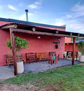 un patio con panche in legno e un edificio rosso di Cabaña Sarita a Santa Rosa