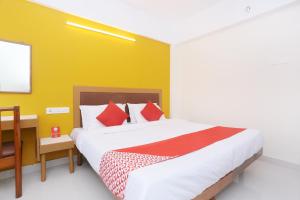 a bedroom with a large bed and a yellow wall at Hotel Ganesh in Trivandrum