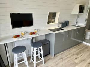 a small kitchen with two stools and a counter with a sink at Yr Onnen in Oswestry