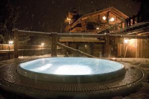 una vasca idromassaggio nella neve di fronte a una cabina di Hotel Chalet Svizzero a Courmayeur