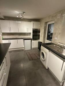 a kitchen with white cabinets and a washing machine at NKY Sweet 3 Bed House Apartment in London