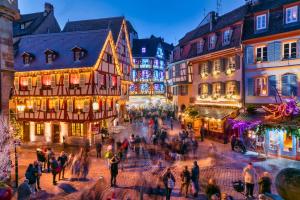 eine Gruppe von Menschen, die nachts durch eine Stadtstraße laufen in der Unterkunft Le petit Châtaignier - Cozy Immo in Châtenois