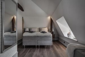 1 dormitorio en el ático con 2 camas y espejo en Trädgårdsmästarbostaden / The Gardeners Villa, en Gävle