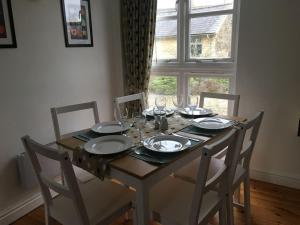 a dining room table with plates and wine glasses at The Stables, Lower Mill Estate in Somerford Keynes