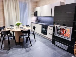 una cucina con tavolo, sedie e camino di Santa's Luxury Boutique Villa, Santa Claus Village, Apt 1 a Rovaniemi