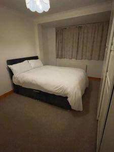 a bedroom with a white bed with a window at NKY Sweet 3 Bed House Apartment in London
