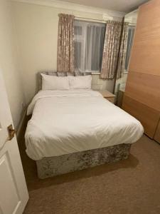 Schlafzimmer mit einem Bett mit weißer Bettwäsche und Kissen in der Unterkunft NKY Sweet 3 Bed House Apartment in London