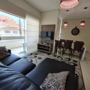 sala de estar con sofá azul y mesa en novo e aconchegante apartamento a 90 metros da praia de bombinhas, en Bombinhas