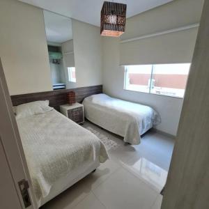 1 dormitorio con 2 camas y espejo en novo e aconchegante apartamento a 90 metros da praia de bombinhas, en Bombinhas