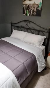 un letto con struttura nera e lenzuola e cuscini bianchi di IL COLOSSEO B&B CASSINO a Cassino
