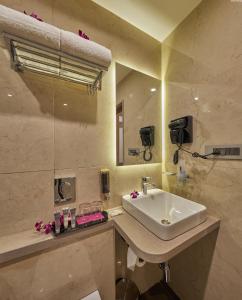 a bathroom with a sink and a mirror at Regenta Inn Grand-ORR, Mahadevapura in Bangalore