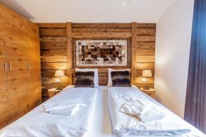 two beds in a bedroom with wooden walls at Chalet Hohe Tauern - Steinbock Lodges in Zell am See