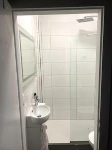 a white bathroom with a sink and a shower at JayBnB - Geräumiges Apartment am Hafen von Dortmund in Dortmund