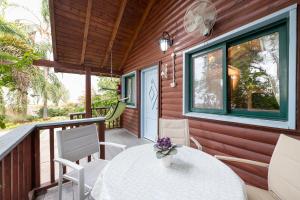 a screened porch with a white table and chairs at Nof Kineret Suites in Moshav Ramot