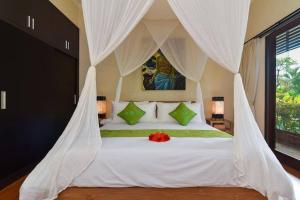a bedroom with a white bed with a canopy at Villa Intan in Legian +11 photos