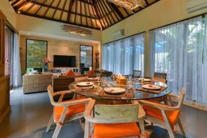 a dining room with a table and chairs and a living room at Villa Intan in Legian