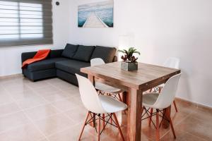 a living room with a wooden table and white chairs at FUERTEVENTURAPARTMENTS in Corralejo