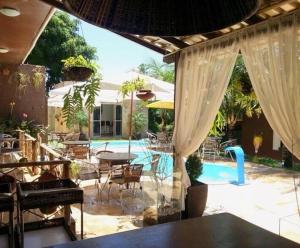 a patio with a table and chairs and a pool at Pousada Recanto do Sal in Salinópolis