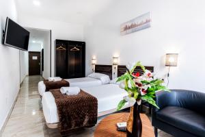 um quarto de hotel com uma cama branca e um sofá em Hostal Rincón de Sol em Madri