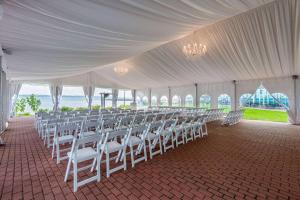 een grote tent met witte stoelen en de oceaan bij 41 Lakefront Hotel, Trademark Collection by Wyndham in Geneva