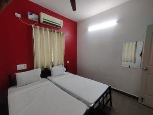 Dos camas en una habitación con una pared roja. en Allamanda Abode, en Chennai 108 fotos más