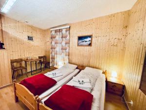 two twin beds in a room with wooden walls at Weisses Rössli in Leukerbad