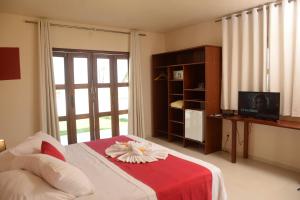 a bedroom with a bed with a red blanket and a television at Red House Pousada in Flecheiras
