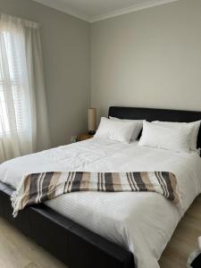 duże łóżko z czarnym zagłówkiem w sypialni w obiekcie Happy Home Rondebosch w Kapsztadzie