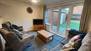 a living room with a couch and chairs and a tv at Graylingwell! 4/5Bedroom House Chichester Goodwood in Chichester
