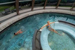 2 personas nadando en una piscina en Renè Dolomites Boutique Hotel en Pozza di Fassa