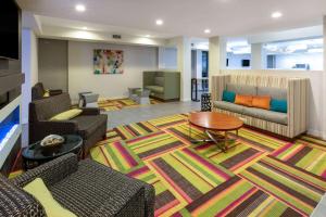 a living room with couches and a table on a rug at La Quinta Inn & Suites by Wyndham Tulsa Downtown - Route 66 in Tulsa