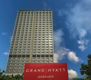 een hoog gebouw met een bord ervoor bij Grand Hyatt Gurgaon in Gurgaon