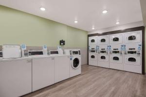 フェニックスにあるWoodSpring Suites Phoenix-Deer Valleyの洗濯機4台とカウンター付きのランドリールーム