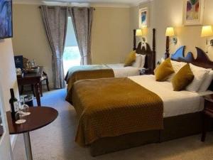 um quarto de hotel com duas camas e uma mesa em Shamrock Inn Hotel em Lahinch