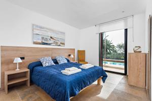 a bedroom with a blue bed with towels on it at Villa Rosa in Punta Prima +68 photos