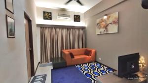 a living room with an orange chair and a television at GWE Homestay in Bayou Lagoon Waterpark Resort Melaka in Malacca