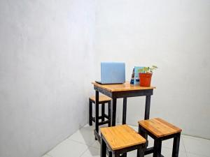 Sunggal的住宿－OYO 91959 La Khansa Homestay Syariah，一张桌子,上面有一台笔记本电脑和两张凳子