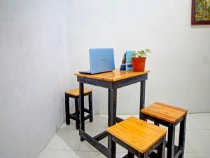 a desk with a laptop on it with two stools at Hotel O La Khansa Homestay Syariah in Sunggal