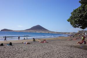 people laying on a beach with a mountain in the background at Medano Nest Hostel in El Médano