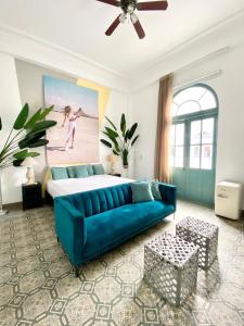 een woonkamer met een blauwe bank en een bed bij AmazINN Places Casco Viejo Pool and Rooftop VIII in Panama-Stad
