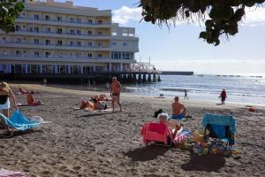a group of people sitting on the beach near the ocean at Medano Nest Hostel in El Médano