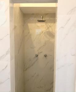 a shower in a bathroom with white marble at AmazINN Places Casco Viejo Pool and Rooftop VIII in Panama City