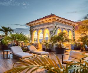 een gebouw met stoelen en palmbomen op een patio bij AmazINN Places Casco Viejo Pool and Rooftop VIII in Panama-Stad