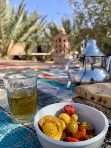 a bowl of vegetables on a table next to a drink at Maison Adrar Merzouga in Merzouga