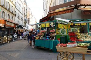 een groep mensen die rond een fruitkraam op straat staan bij Le Loft Levis in Parijs